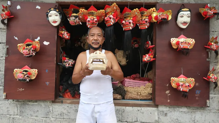 Wayan Madru carves and decorates the masks used in Balinese traditional dance. They are popular purchases for tourists [Erwin Pietersz/Al Jazeera