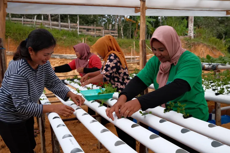 Sri Sudarwati (left), whose parents moved to the area from Java in the 1970s, said the roads built for new capital development have shortened the time it takes for her to travel from her village to the closest major city, Balikpapan, from almost three hours to just one [Jessica Washington/Al Jazeera]